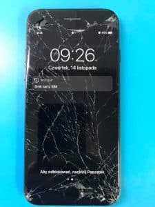 Telefon z szybą rozbitą na całej powierzchni, ekran mimo to wyświetla ekran blokady